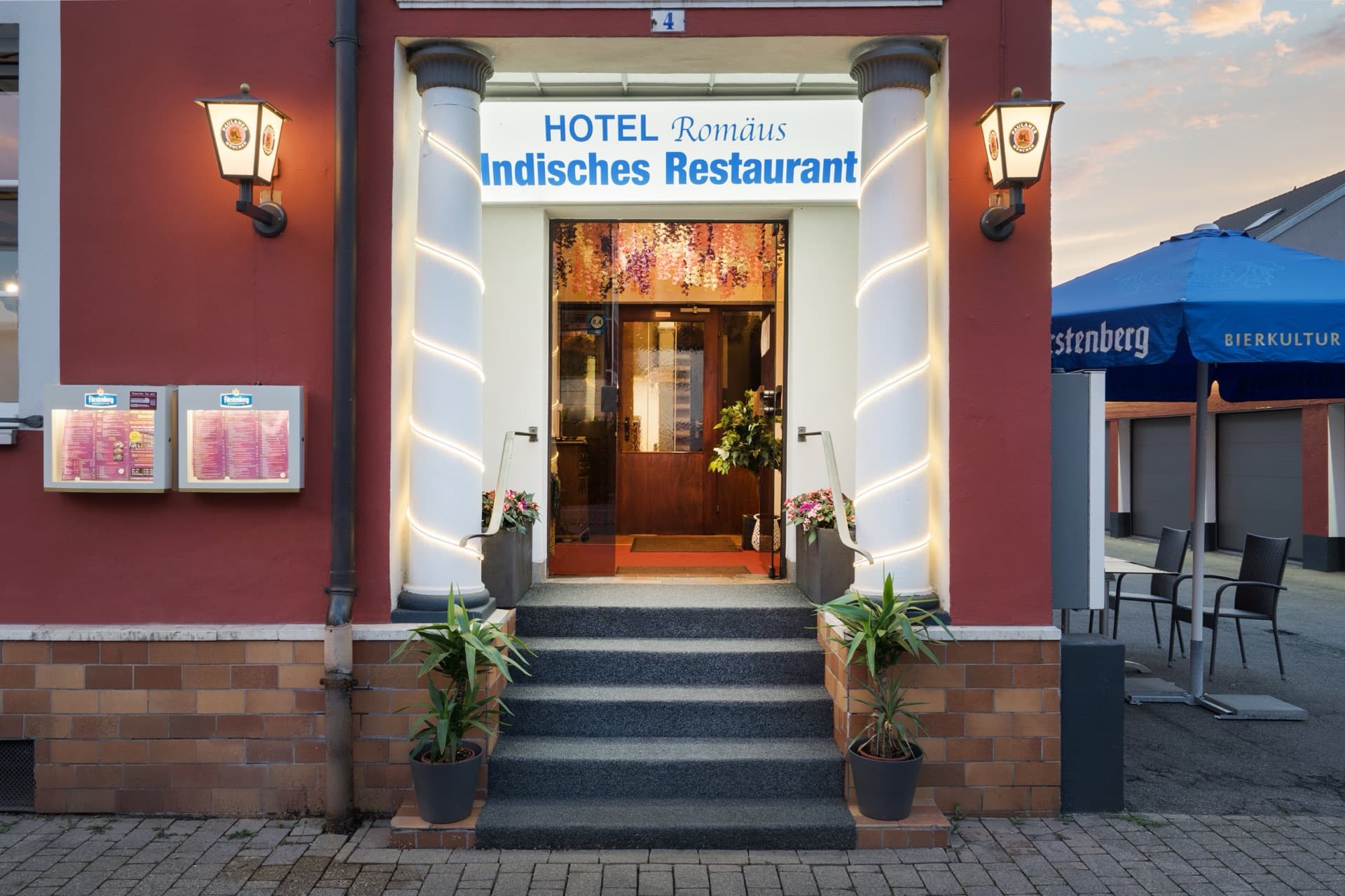 Der beleuchtete Eingang des Hotel Romäus am Abend — hier kommen Sie an