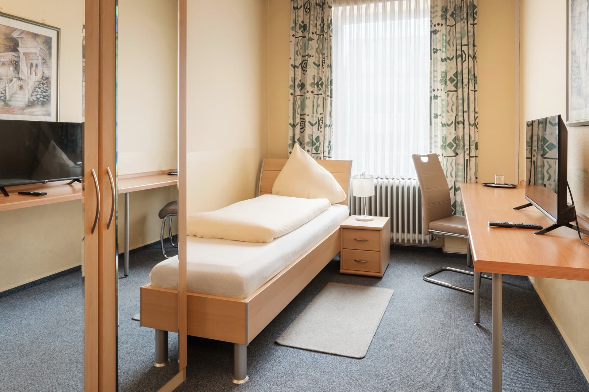 Einzelzimmer mit Schreibtisch, TV und Kleiderschrank